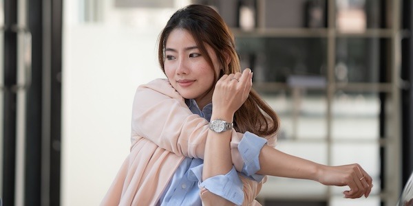 Young businesswoman stretching with hand raised while sitting on a chair in an office. Young businesswoman stretching with hand raised while sitting on a chair in an office.